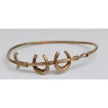 Edwardian bangle in the form of horseshoes and and crop marked 15ct gold, 4.6g, 5.6 x 5.2cm