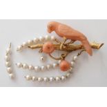 An 18ct gold brooch in the form of a parrot on a branch, the parrot of carved coral set with a
