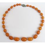Baltic amber necklace of 28 graduated oval beads, the largest 21.2x15.5mm, interspersed with faceted