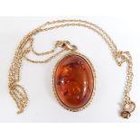 A 9ct gold pendant set with a pressed amber cabochon on a 9ct gold chain