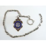 A silver watch chain with a hallmarked silver and 9ct gold fob set with enamel reading 'Sefton