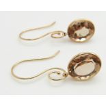 A pair of 14k gold earrings set with oval cut quartz