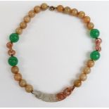 A jade necklace with elongated carved bead suspended from 20 spherical mutton fat beads, four larger