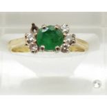 An 18ct gold ring set with a round cut emerald set with diamonds, 2.4g, size I