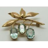 A gold brooch/ pendant set with three oval aquamarines