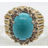 An 18ct gold bi-coloured ring set with a turquoise cabochon surrounded by diamonds, 9.2g, size J