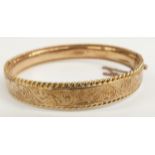 9ct gold bangle with scrolling decoration and rope twist edge, 14.8g, 5.7 x 5cm