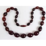 An amber necklace of 27 graduated oval beads, the largest 21.1x16.7, 60g.