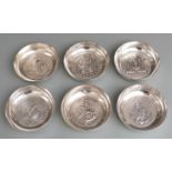 Set of six white metal shallow bowls or trays, each with shipping interest medallion to base, one