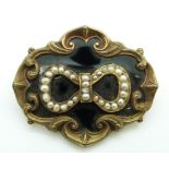 Victorian mourning brooch set with seed pearls to the centre in a bow on black enamel ground within