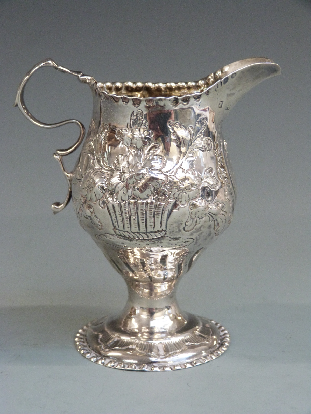 George II hallmarked silver jug with embossed decoration, London 1759 maker's mark rubbed, height