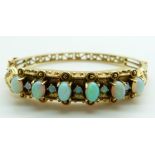 A 14k gold bangle set with six oval opal cabochons interspersed with round opal cabochons, 25.2g,