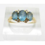 An 18ct gold ring set with three oval blue topaz and diamonds, 3.9g, size O
