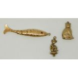 Two 9ct gold charms comprising a cat and a pixie (3.4g) and a yellow metal reticulated fish (2.3g)