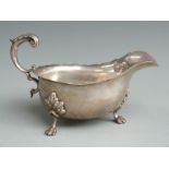 Edward VII hallmarked silver sauce boat with shaped edge, raised on paw feet and with scroll handle,