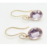 A pair of 14k gold earrings set with an oval cut amethyst to each