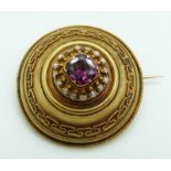 Victorian Etruscan Revival gold brooch set with a cushion cut garnet surrounded by seed pearls