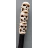 A walking stick with carved marine ivory handle depicting three skulls, 91cm long