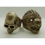 Two oriental style white metal rings, one in the form of a dragon mask, the other as a skull,