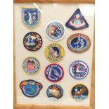 Twelve cloth Apollo space exploration badges or patches in glazed frame
