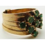 A 14k gold ring made up of five bands set with nine round cut emeralds, 5.5g, size K