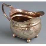 Georgian hallmarked silver cream or milk jug with engraved decoration raised on four ball feet,
