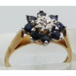 A 9ct gold ring set with a diamond surrounded by sapphires, 3.0g, size M