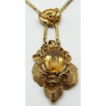 A 15ct gold necklace set with an oval cut citrine within an engraved foliate and filigree border,