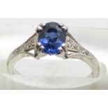 A platinum ring set with an oval cut sapphire of approximately 1ct and diamonds to the shoulders,