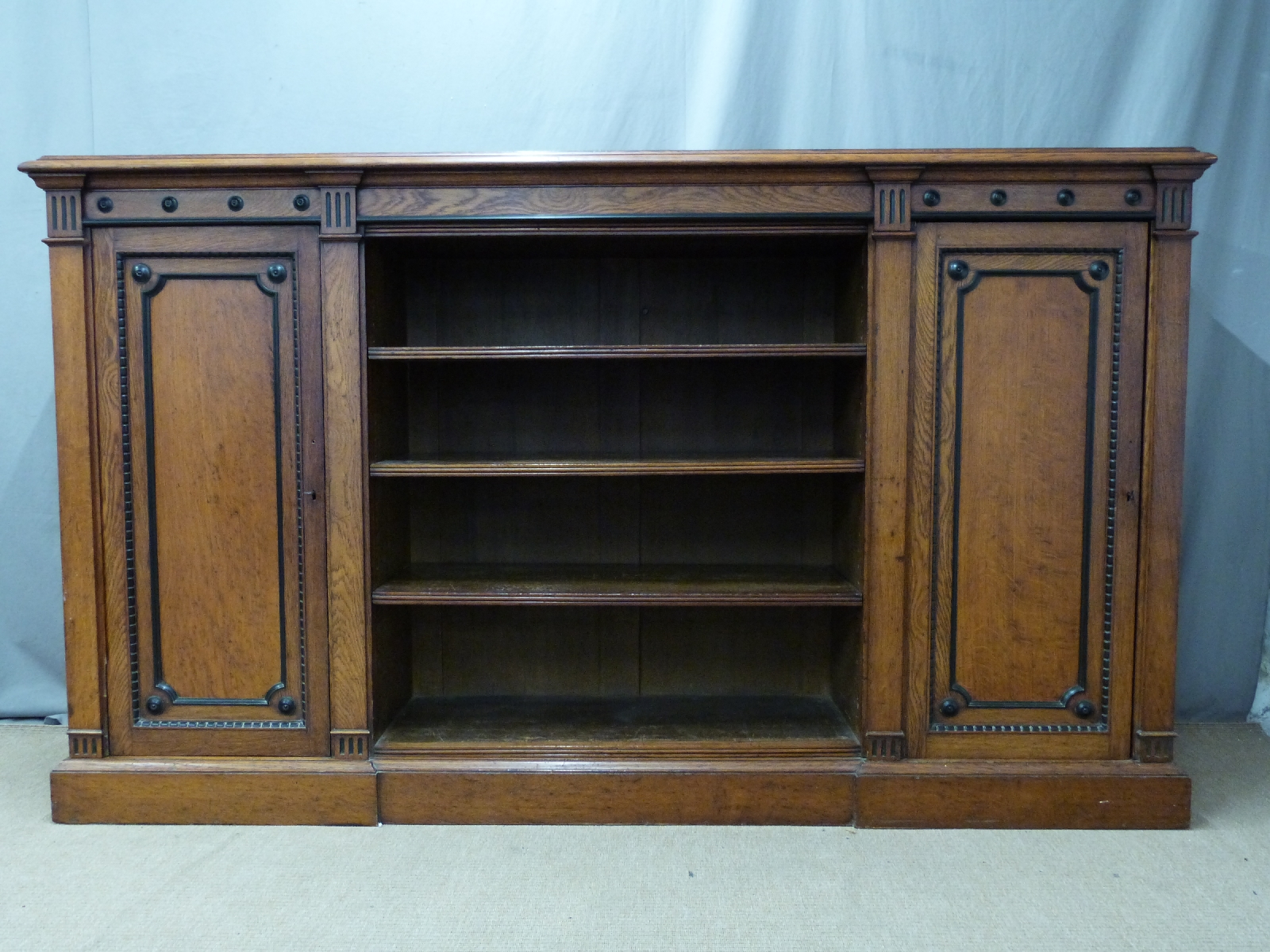 19thC oak bookcase with carved and ebonised detail, the central shelves flanked by two cupboards,