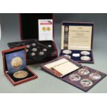 Four deluxe cased coin sets comprising commemorative gold plated and silver plated coins with enamel