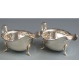 Pair of hallmarked silver sauce boats with shaped edges, raised on three feet, Sheffield 1953 and