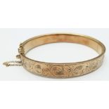 A 9ct gold bangle with engraved decoration, 12.7g