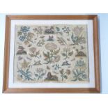 A 17thC cross stitch/embroidery decorated with flora and fauna mounted on linen in glazed frame.