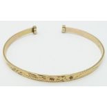 A 9ct gold bangle with engraved decoration, 5.4g