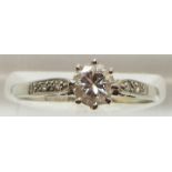 A platinum ring set with a round cut diamond measuring approximately 0.5ct, with diamond encrusted