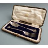 George V hallmarked silver spoon and fork christening set, decorated with winged cherub faces to