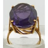 A yellow metal ring set with a large oval cut synthetic purple sapphire, 9.3g, size L