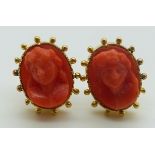 A pair of yellow metal earrings set with carved coral cameos within a sphere border