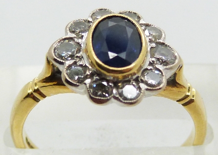 An 18ct gold ring set with an oval cut sapphire surrounded by diamonds, 4.3g, size N