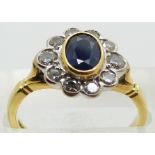 An 18ct gold ring set with an oval cut sapphire surrounded by diamonds, 4.3g, size N