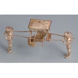 Chinese white metal novelty model of two men carrying a chair with filigree roof and seat, with