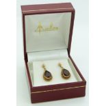 A pair of 14ct gold earrings set with a pear cut garnet to each