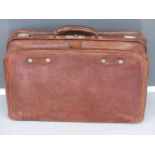 Vintage leather Gladstone bag style suitcase with filled interior and metal trim.