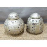 Two white metal overlaid lidded coconut jars with embossed detail, tallest 13.5cm
