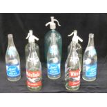 Three vintage soda siphons, two with Schweppes to front, branded club soda and other bottles