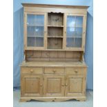 Pine dresser, the top having central shelves flanked by glazed display cupboards, the base fitted