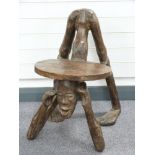 A carved tribal art wooden stool in the form of a man on all fours