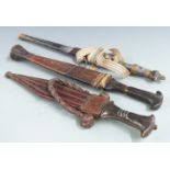 Three African/Asian tribal daggers each with leather scabbard and shaped handle, longest 36cm
