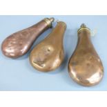 Three copper and brass powder flasks one stamped 'Patent', largest 19.5cm long.